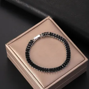Elegant silver-toned bracelet with rectangular black zircons on a gold gift box.