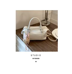 Vue détaillée du sac Boston en cuir souple blanc crème avec un charm ours