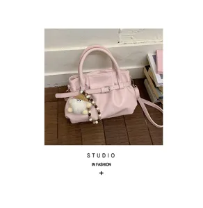 Detailansicht der rosa Handtasche mit Plissee-Design, Gürtel und Plüsch-Schlüsselanhänger