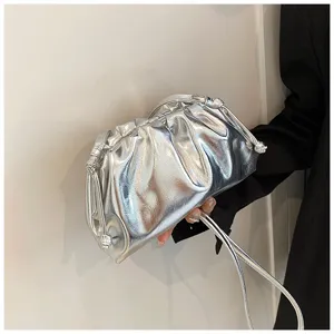 Gedetailleerde close-up van een zilveren geplooide cloudtas met een luxe lakafwerking.