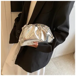 Metallic zilveren geplooide wolktas getoond met een model in een zwarte blazer
