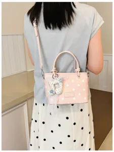 Nahaufnahme einer rosa gepunkteten Beuteltasche mit Musiknoten-Anhänger und Spitze.
