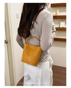 Woven yellow leather bucket bag worn by model in a minimalist lifestyle setting