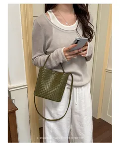 Sophisticated olive green woven bucket bag showcased by a model in a retro indoor setting
