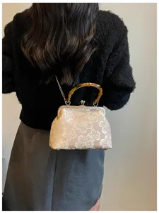 Vintage shell evening clutch featuring floral embroidery and natural bamboo handle detail