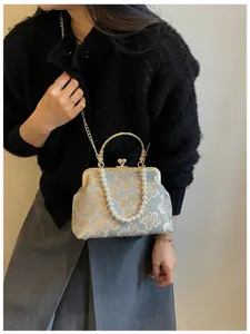 Elegant blue embroidered floral evening bag with pearl handle and gold chain strap.