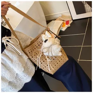 Detailaufnahme der beigen Beuteltasche mit Laser-Cut und weißem Plüschbär-Anhänger