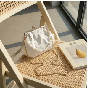 Primer plano de un elegante bolso de noche tipo concha blanco con asa de perlas y bordado