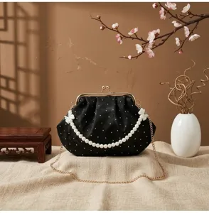 Detalle de bolso de noche vintage con lunares negros y elegante correa de perlas