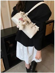 Detailansicht einer weißen Baguette-Tasche aus Lackleder mit süßem Plüschbär-Anhänger