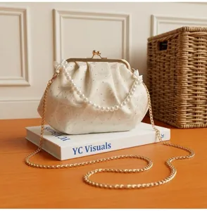 Primer plano de elegante bolso de noche blanco bordado con rosas, perlas y cadena oro