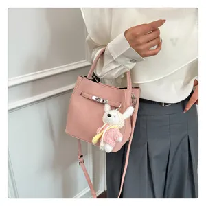 Rosa Eimer-Tasche mit Lychee-Muster, Schlossverschluss und Plüschhasen-Anhänger am Model