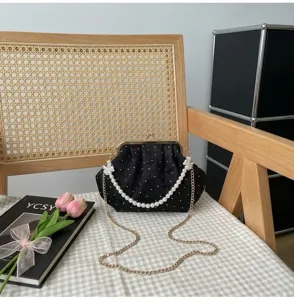 Detalle de bolso de noche negro con lunares blancos y asa de perlas elegante