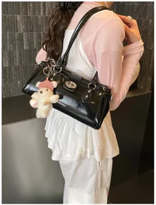 Detailaufnahme schwarze Retro-Baguette-Tasche mit Schloss und Plüschbär-Anhänger