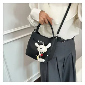 Moderne schwarze Eimertasche mit Litschi-Muster, Schlossverschluss und Plüsch-Hundeanhänger