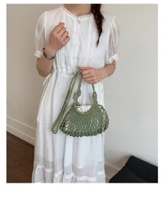 Vue détaillée d'un mannequin tenant un sac seau en maille verte avec doublure blanche.