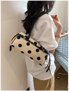 Detailansicht einer Polka-Dot-Baguette-Tasche aus Canvas mit schwarzen Schnallen.