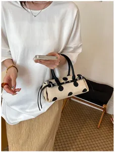 Elegante cremefarbene Canvas-Baguette-Tasche mit schwarzen Punkten in Lifestyle-Detailansicht