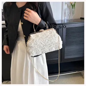Detail view of white 3D rose floral texture and gold rhinestone clasp on evening clutch
