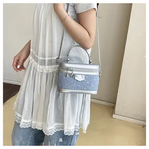 Side view of a model wearing a denim blue vanity box bag with silver trim and star charms