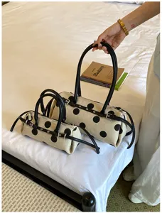 Detail von zwei gepunkteten Canvas-Baguette-Taschen mit Ledergürtelschnallen auf einem Bett.