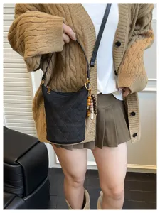 Modelo con bolso cubo acolchado negro con cuentas y chaqueta de punto color camel