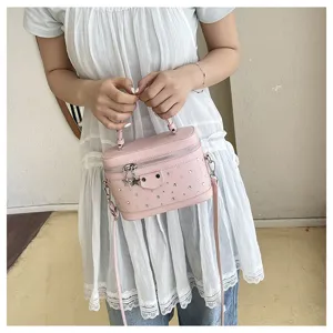 Detailed view of a pink box-shaped cosmetic handbag with metal studs and a star charm