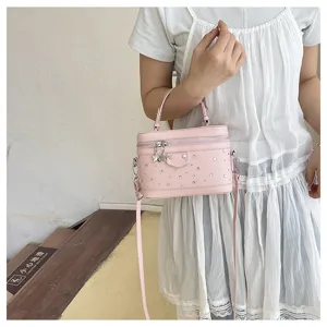 Close-up of a pink rhinestone box vanity bag with star charms carried by a model.