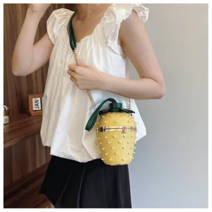 Modische gelbe Erdbeer-Eimertasche mit Perlenbesatz und Goldkette am Modell getragen