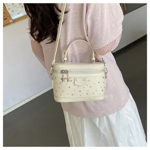 Close-up detail of a cream white box handbag featuring rhinestone studs and star-shaped zippers