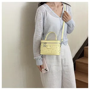 Yellow studded vanity box handbag shown in a lifestyle model shot indoors scene