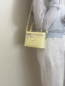 Pale yellow vanity box bag with silver studs and star charms for women's summer style.
