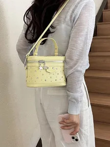 Stylish light yellow box-shaped crossbody bag with star charms and silver stud details