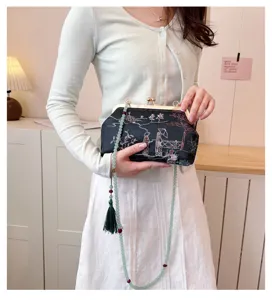 Dettaglio elegante pochette ricamata nera con tracolla in perline verdi e nappina
