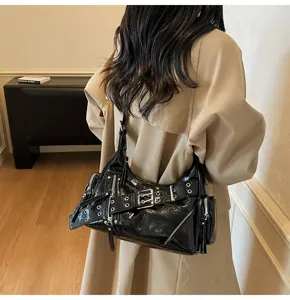 Close-up of a black patent leather motorcycle shoulder bag with buckle details.