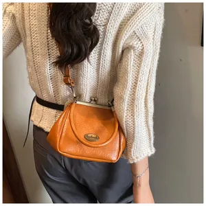 Petit sac à main vintage avec fermoir à clip en cuir souple marron orangé élégant.