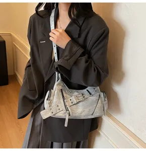 Chic metallic silver motorcycle underarm bag with belt buckle and zipper details on model
