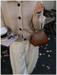 Détail d'un sac vintage en cuir souple marron porté par un mannequin en automne