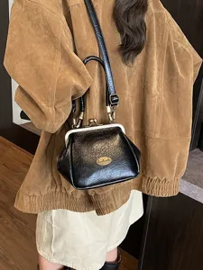 Sac coquillage rétro en cuir noir souple avec fermeture à fermoir vintage chic.