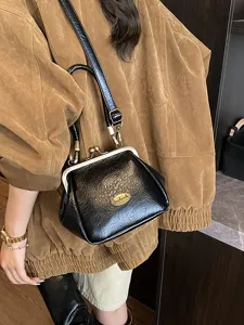 Sac à main vintage noir en cuir souple avec un élégant fermoir à clip en métal doré