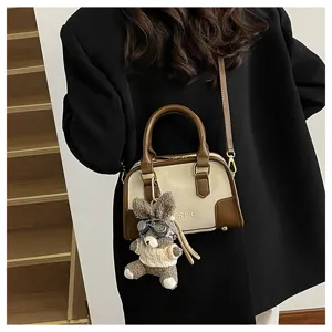 Detailed view of cream and brown crossbody pillow bag with cute teddy bear charm accessory