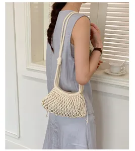 Détail d'un sac seau en filet tissé blanc avec cordon sur l'épaule d'un modèle.