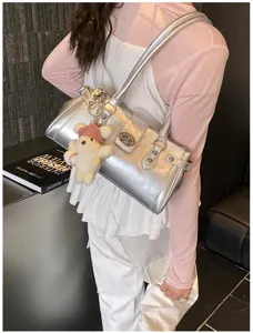 Detailansicht der silbernen Metallic-Baguette-Tasche mit Schloss und Bärenanhänger.