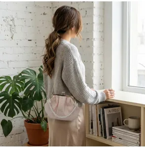 Bolso de noche bordado con forma de caracola rosa y perlas en un ambiente hogareño