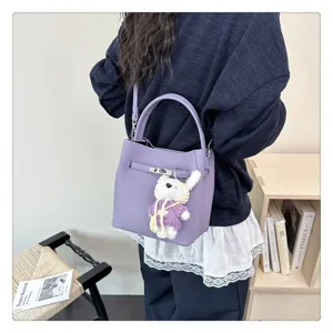 Detailansicht einer lila Eimertasche mit Lychee-Struktur und silbernem Schloss-Anhänger.