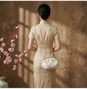 Elegante bolso de noche blanco bordado con asa de perlas sobre modelo de Cheongsam