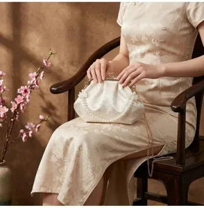Detalle de un bolso de noche con perlas y bordados, combinado con un vestido cheongsam.