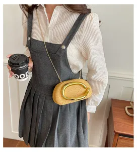 Close-up of a pleated shell acrylic evening clutch featuring a bold gold oval handle.