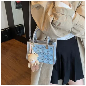 Detailed view of the denim blue sequined tote bag featuring woven handle and teddy charm