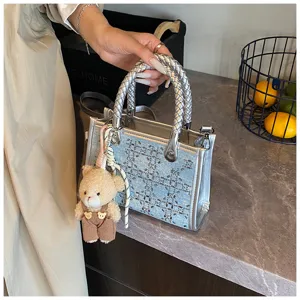 Blue denim tote bag with silver braided handles and sparkling sequin pattern detail